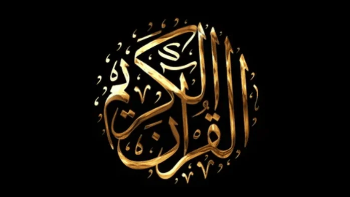 مصحف مفتوح مكتوب عليه خط معقد على صفحاته، موضوع على حامل خشبي.